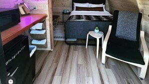 A cozy attic bedroom with a bed, a small table, a chair, and a desk with a microwave. - The Bike Inn #16, White River Cabin (Bentonville)
