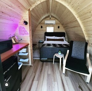 Un dormitorio acogedor en el ático con cama, una mesita, una silla y un escritorio con microondas.