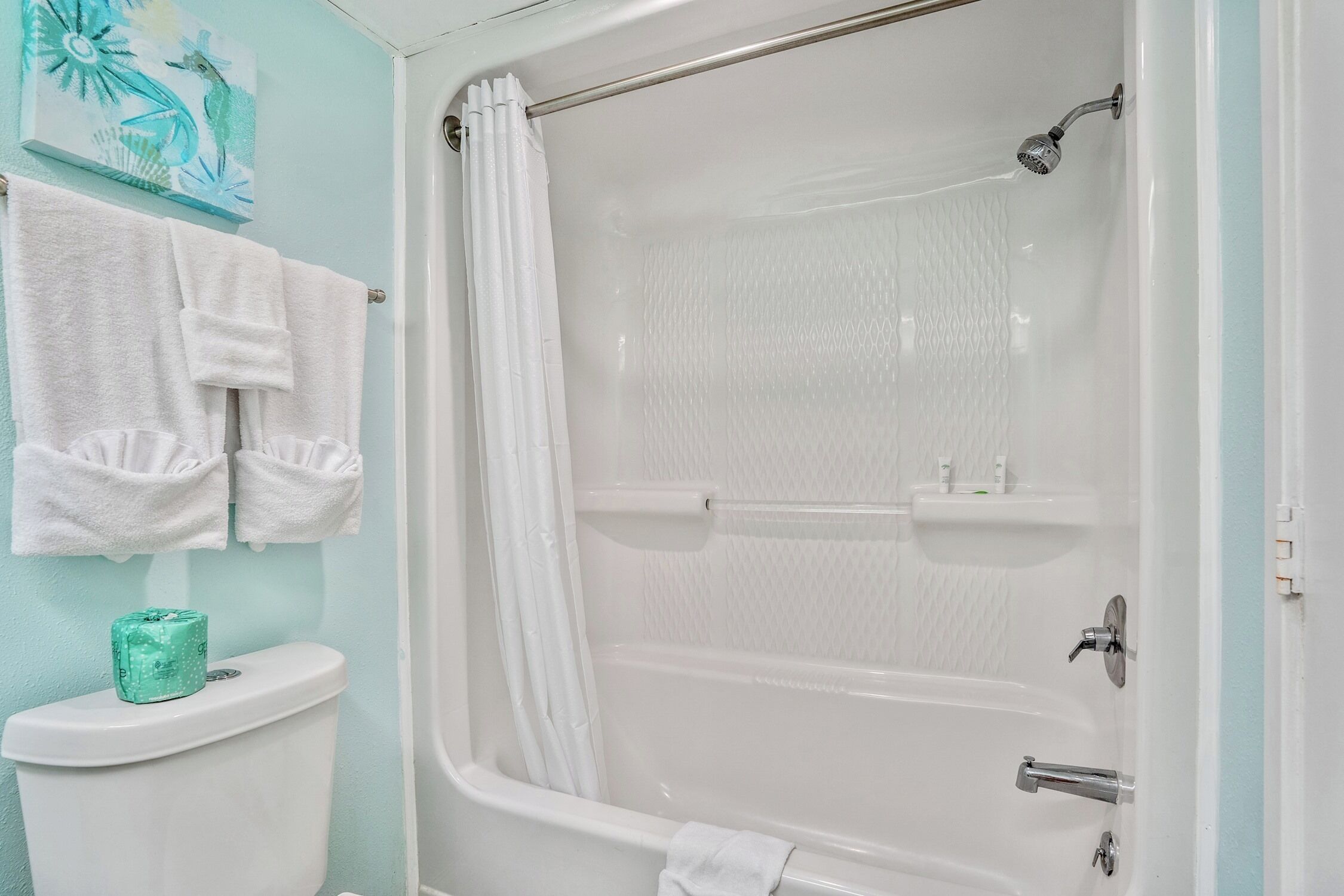 A bathroom with a shower, toilet, and two towels hanging on the wall.