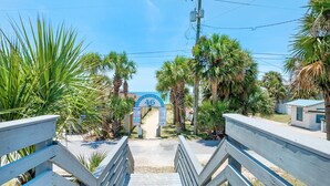 A wooden staircase leading to a beach entrance with palm trees and a clear blue sky. - Vista del Mar I - Short Walk to the Beach 301 (Panama City Beach)