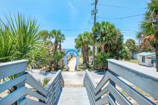 A wooden staircase leading to a beach entrance with palm trees and a clear blue sky. - Vista del Mar I - Short Walk to the Beach 301 (Panama City Beach)