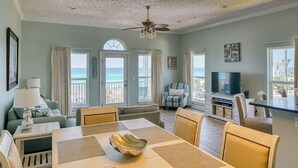 A spacious living room with a dining area, a television, and a balcony with ocean views. - Vista del Mar I - Short Walk to the Beach 301 (Panama City Beach)