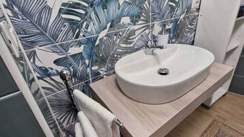 Une salle de bain avec un lavabo blanc, un meuble-lavabo en bois et un miroir au-dessus du lavabo.