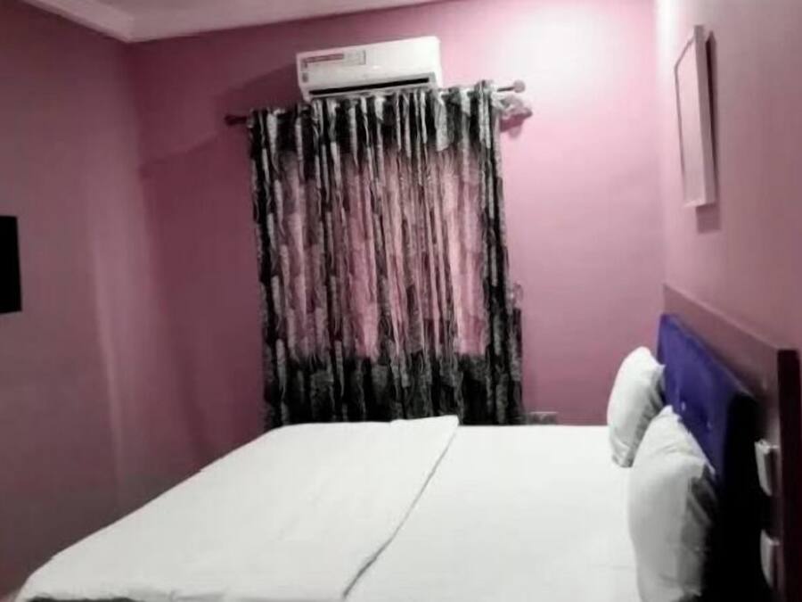 A room with a bed, an air conditioner, and a curtain.