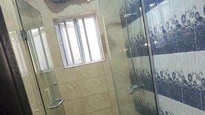 A bathroom with a glass-enclosed shower, a toilet, and a window. - Fibis Hotel (Lekki)