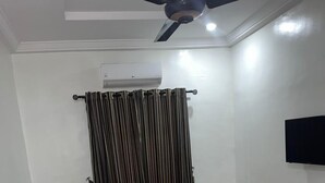 A living room with two sofas, a coffee table, a ceiling fan, and a mounted TV. - Fibis Hotel (Lekki)