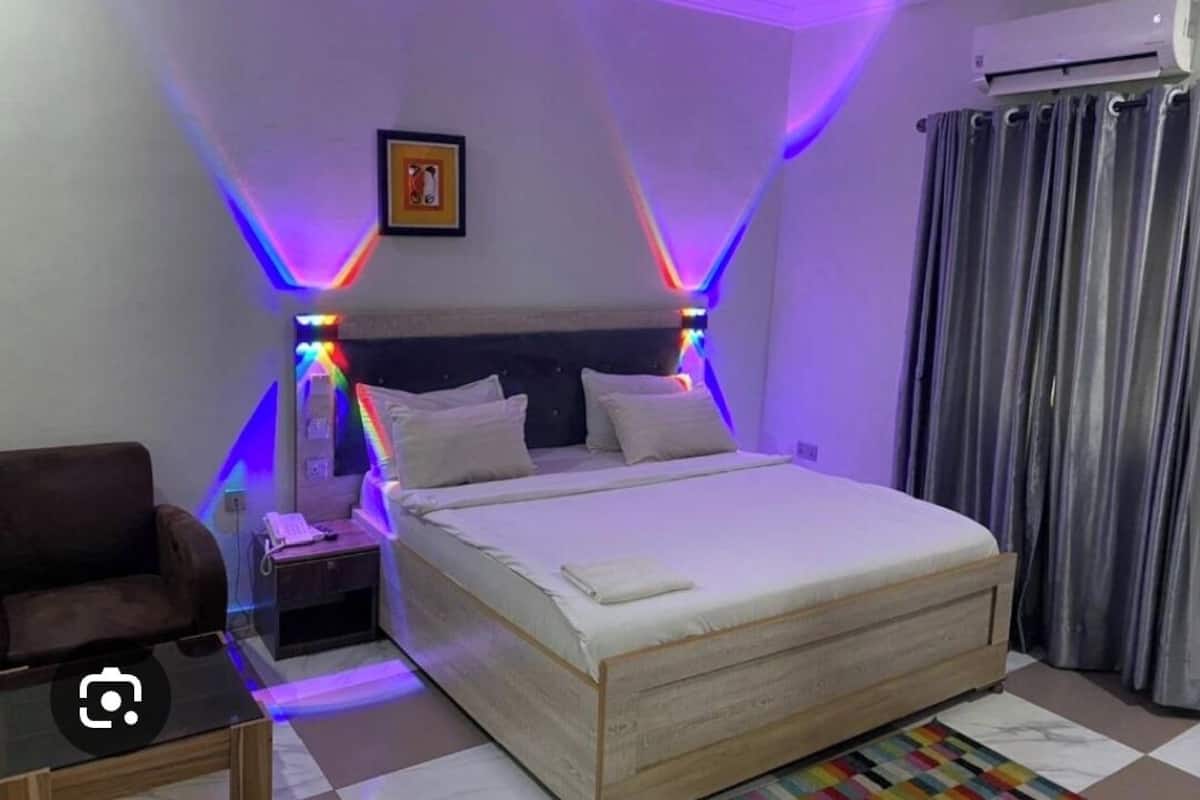 Un dormitorio ordenado con cama, mesita de noche y una silla.