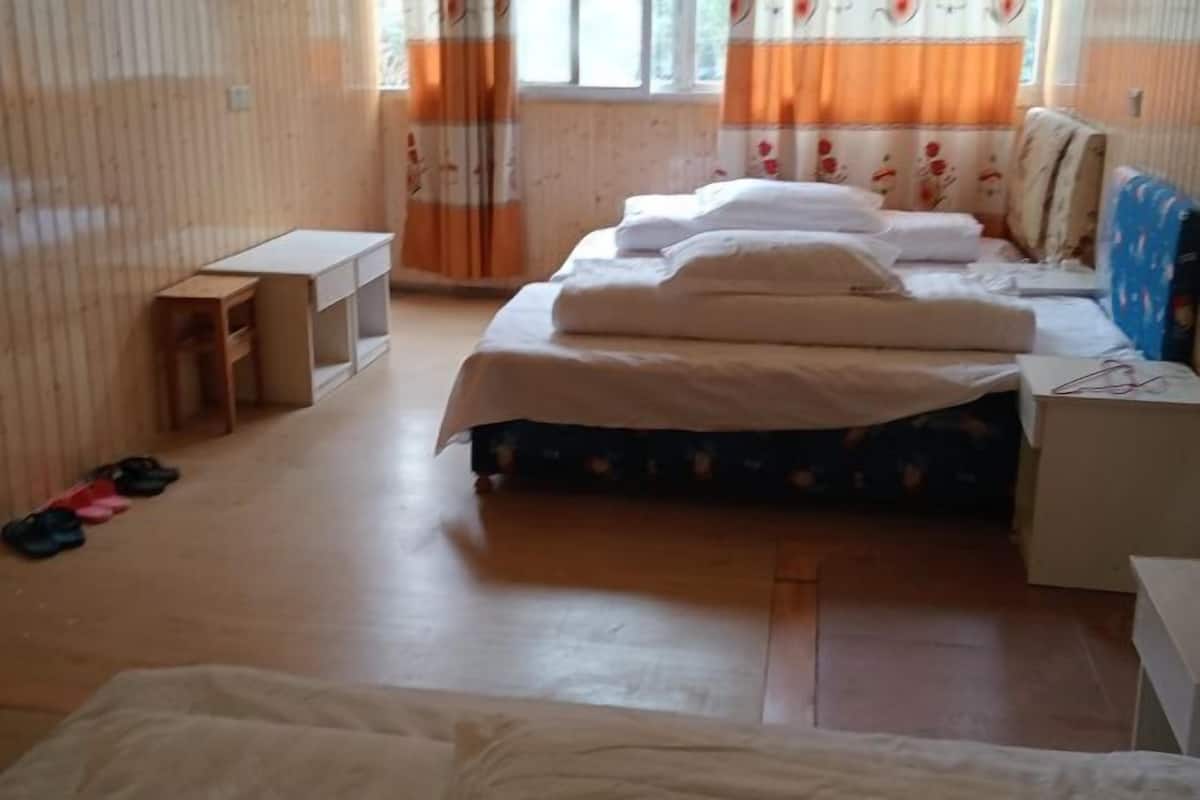 Ein Zimmer mit einem Bett, einem kleinen Schreibtisch und einem Fenster mit Vorhängen.