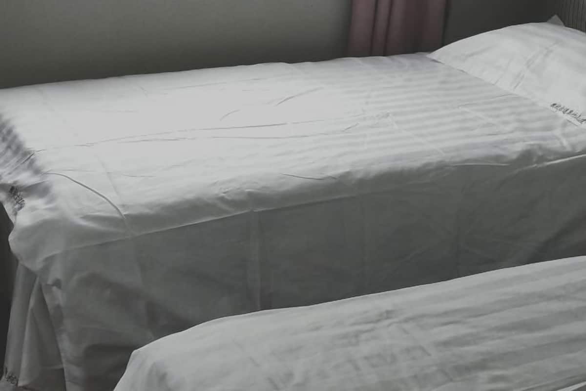Ein Einzelbett mit weißer Bettdecke und Kissen.