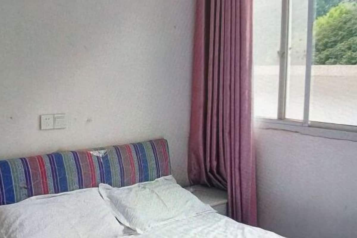 Ein Zimmer mit Bett, einem Vorhangfenster und einer Steckdose.