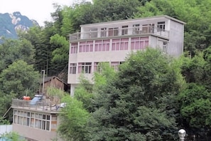 A multi-story building with balconies, surrounded by dense greenery and mountains in the background. - Jixi Huihanggudao Cuizhu Mountain Villa (Jixi)
