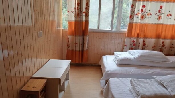 A room with wooden walls, a white bed, a wooden bench, and a window with orange curtains. - Jixi Huihanggudao Cuizhu Mountain Villa (Jixi)