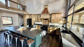 Una cocina moderna con armarios de madera, una isla grande con taburetes y vistas al exterior a través de ventanas amplias.