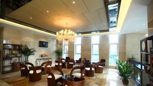 A spacious lobby with a high ceiling, a chandelier, and a seating area with wooden chairs and tables. - Yuchenyuan Hotel (Shuozhou)