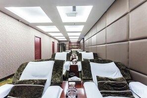 Habitación de hotel con un largo pasillo, varias camas y una mesa central con artículos de cortesía.