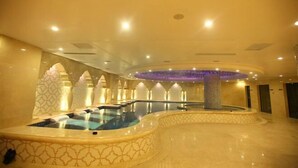 A luxurious indoor pool area with a central hot tub, surrounded by patterned walls and a circular seating area. - Yuchenyuan Hotel (Shuozhou)