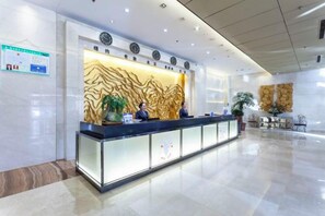 A hotel reception area with a modern design, featuring a reception desk, a decorative wall, and a seating area with chairs and a plant. - Yuchenyuan Hotel (Shuozhou)