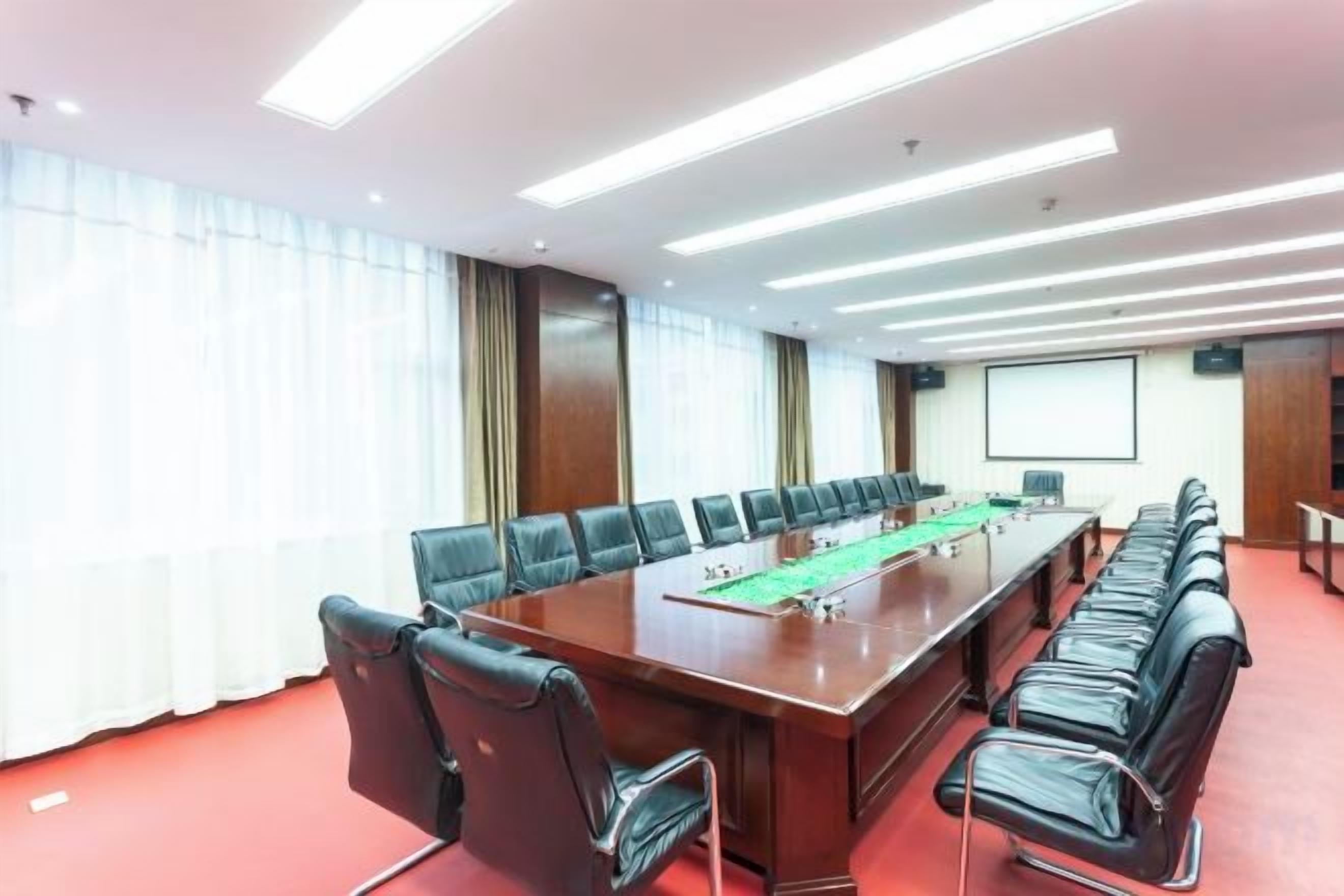 A conference room with a long table, multiple chairs, and a projector screen.