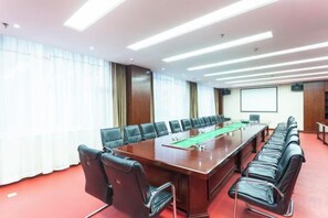 Un salón de conferencias con una mesa larga, varias sillas y una pantalla de proyector.