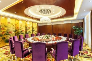A conference room with a round table, purple chairs, and a chandelier.