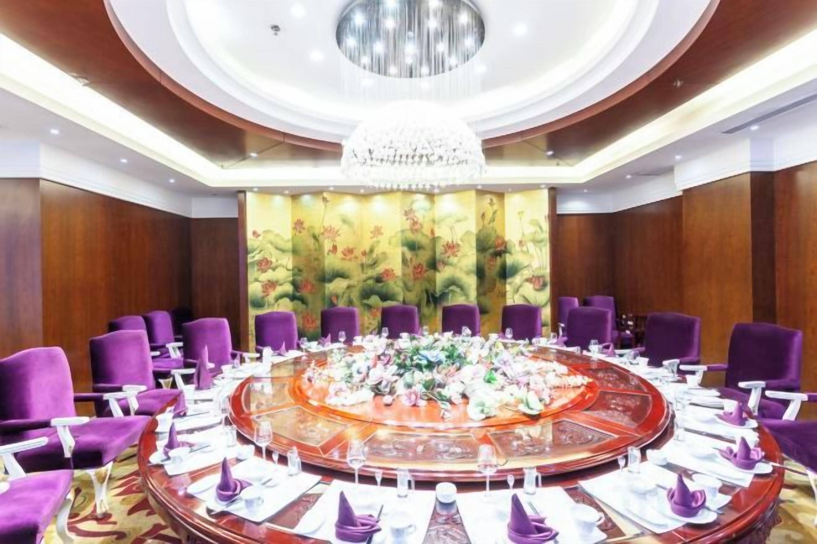 A conference room with a round table, purple chairs, and a chandelier.
