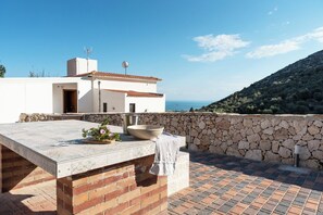Una terrazza sul tetto con un muro in pietra, una grande ciotola e un'esposizione di fiori.