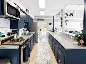 A modern kitchen with a central island, stainless steel appliances, and a view of the outdoors.