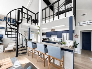 A modern kitchen with a central island, bar stools, and a spiral staircase.