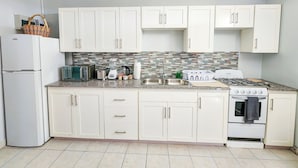 Una cocina con gabinetes blancos, un microondas integrado, una estufa y un refrigerador.