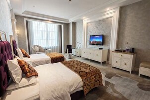A hotel room with two beds, a television, a desk, and a large window.
