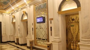 A hotel lobby with marble columns, a checkered floor, and a large screen on the wall. - Royal Hotel (Xiaoyi)