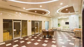 A hotel lobby with a check-in counter, seating area, and a large mirror.