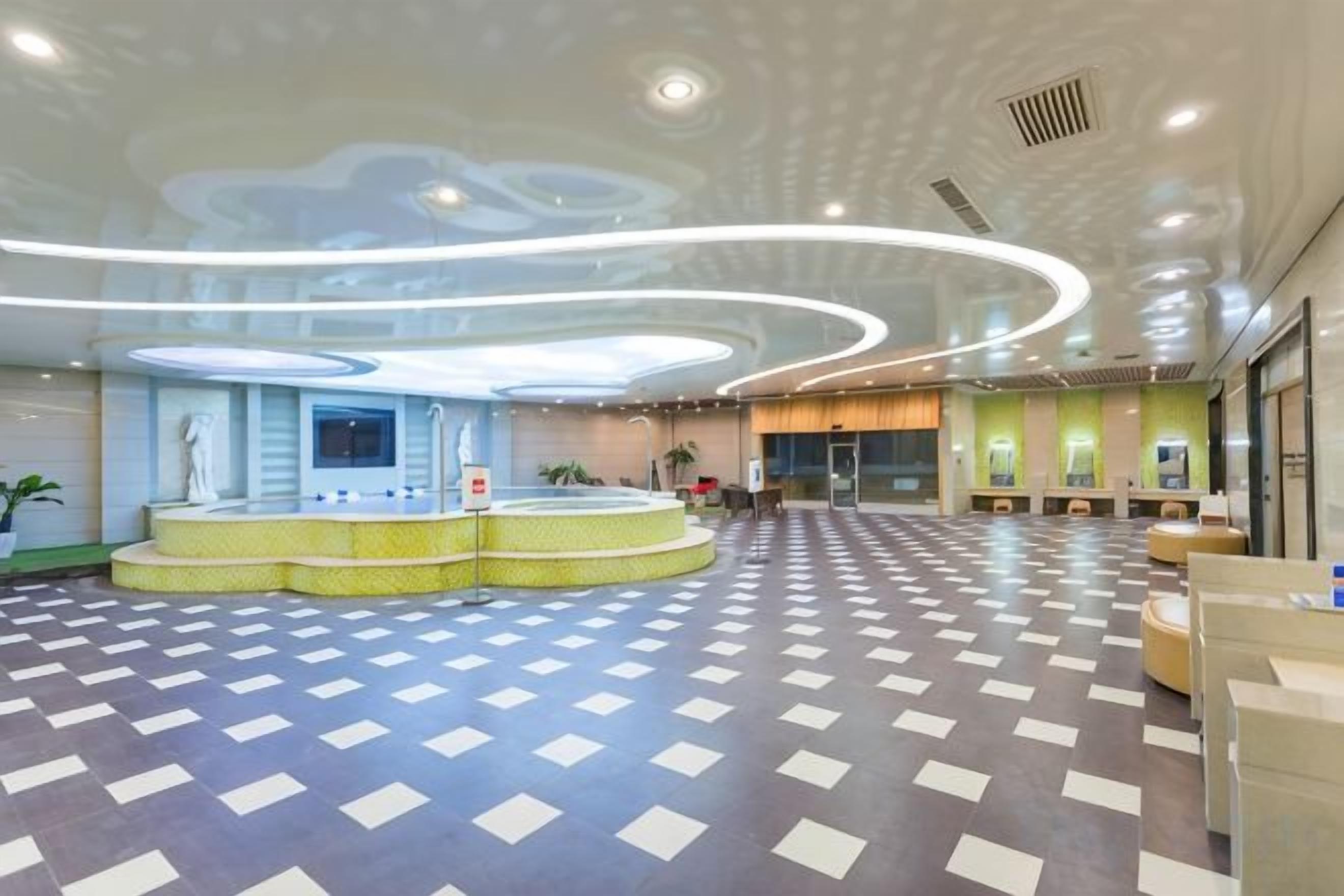 A spacious lobby with a checkered floor, a reception desk, and a statue.