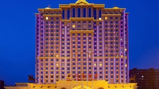 A multi-story hotel with a symmetrical facade, large windows, and a central entrance with a decorative archway. - Royal Hotel (Xiaoyi)