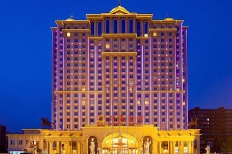 A multi-story hotel with a symmetrical facade, large windows, and a central entrance with a decorative archway.. Royal Hotel