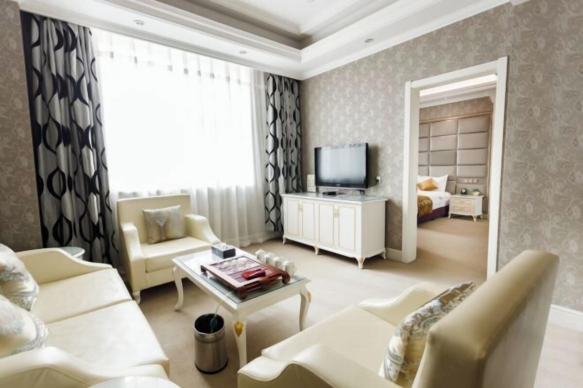 A living room with a sofa, armchairs, a coffee table, a television, and a cabinet.
