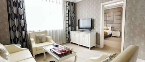 Una sala de estar con sofá, sillones, una mesa de centro, televisor y aparador.