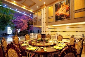 Un comedor formal con sillas ornamentadas y una mesa redonda dispuesta para una comida.