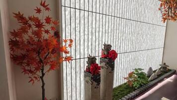 A traditional Japanese-style interior with a wooden wall, a bonsai tree, and stone lanterns.