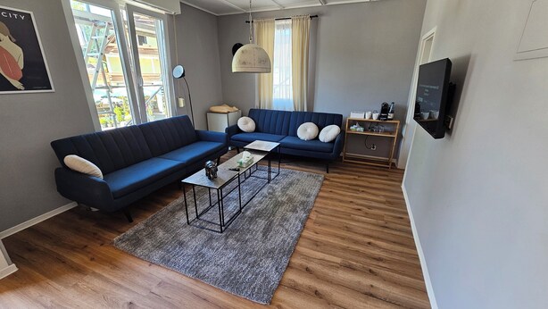Un salon avec un canapé bleu, une table basse et un téléviseur fixé au mur.