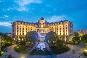 A large, multi-story building with a symmetrical facade, central entrance, and a fountain in the courtyard. - Shanghai Pudong Lingang Kaiyuan Hotel (Shanghai)
