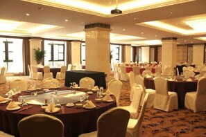 A banquet hall with round tables, white chairs, and a carpeted floor. - Shanghai Pudong Lingang Kaiyuan Hotel (Shanghai)