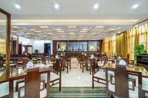 A spacious dining area with multiple tables and chairs, a bar in the background, and a modern ceiling design. - Shanghai Pudong Lingang Kaiyuan Hotel (Shanghai)