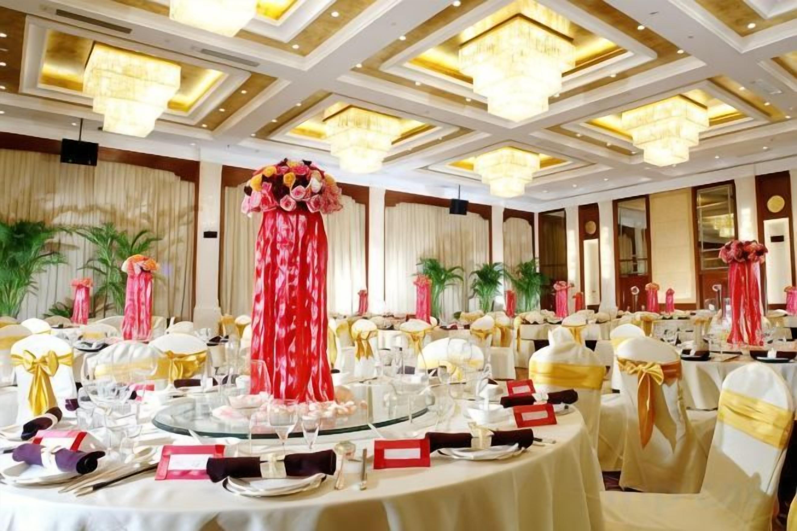 A banquet hall with round tables, chairs, and floral centerpieces.