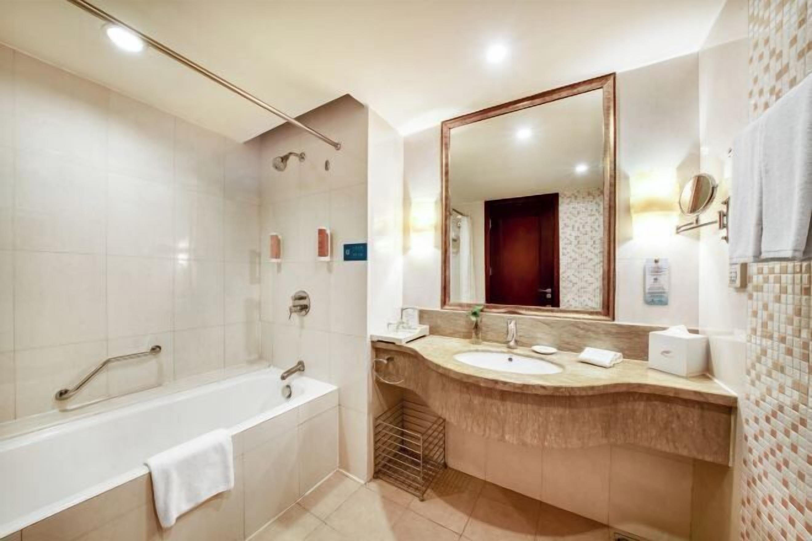 Une salle de bain moderne équipée d’une baignoire, d’un lavabo, d’un grand miroir et d’un espace douche.