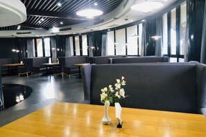 A modern restaurant with high-backed booths and a central table with a vase of flowers. - Shanghai Pudong Lingang Kaiyuan Hotel (Shanghai)