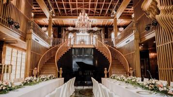 Un salón imponente con una escalera central, un candelabro y un piano.