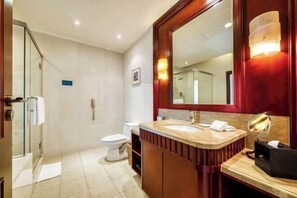 A bathroom with a glass shower enclosure, a toilet, a sink with a vanity, and a large mirror. - Shanghai Pudong Lingang Kaiyuan Hotel (Shanghai)