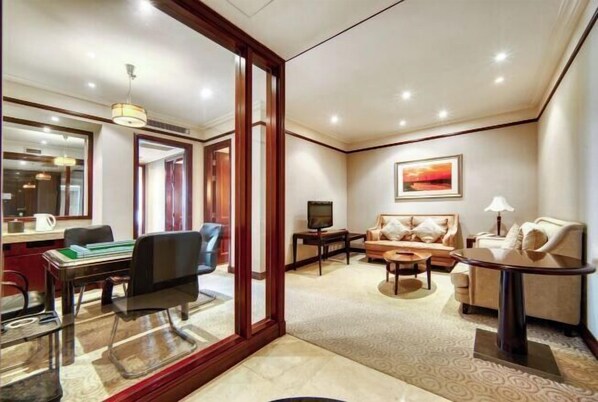 A hotel room with a dining area, a sofa set, a television, and a painting on the wall. - Shanghai Pudong Lingang Kaiyuan Hotel (Shanghai)