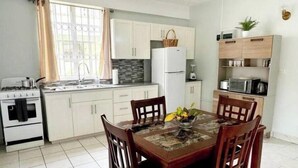 Cucina compatta con mobili bianchi, un fornello e un tavolo da pranzo con sedie.